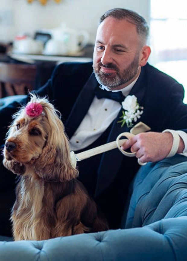 The groom sits with his dog on the sofa at his wedding day